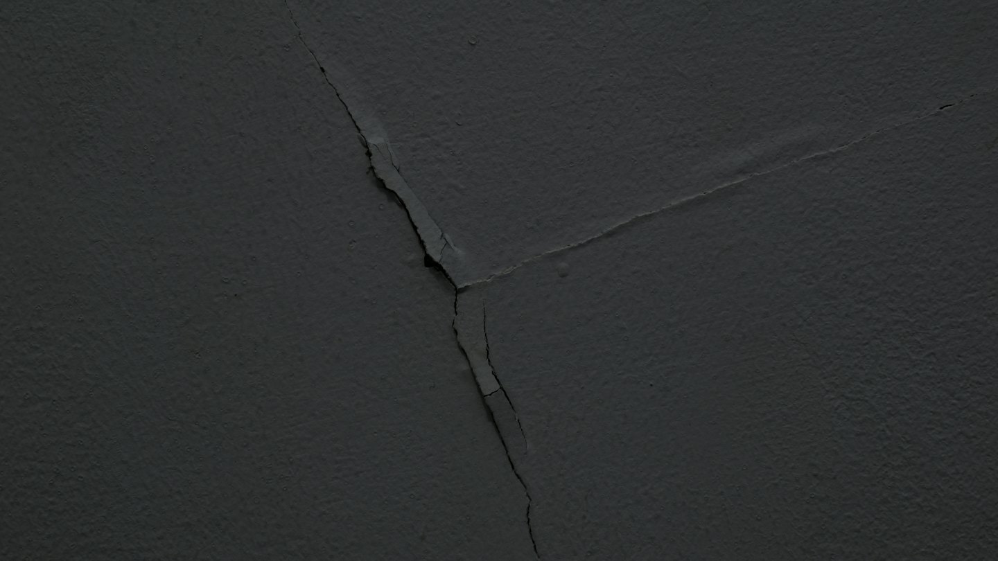 Cracked dark grey wall showing signs of structural damage.